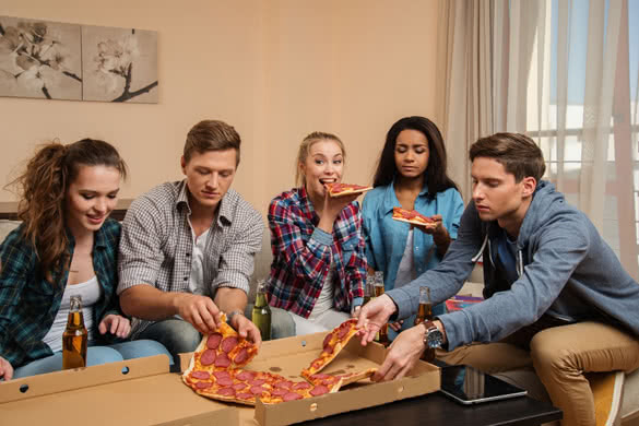 Group-of--friends-with-pizza-and-bottles-of-drink-celebrating-in-apartment