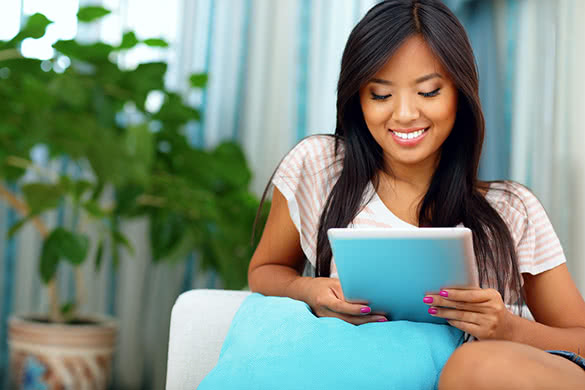 Happy-young-asian-woman-browsing-internet-with-her-tablet