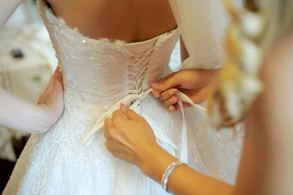 bridesmaid-tying-bow-on-wedding-dress