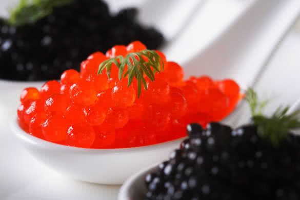 delicacy red and black caviar fish macro in white spoons on a plate