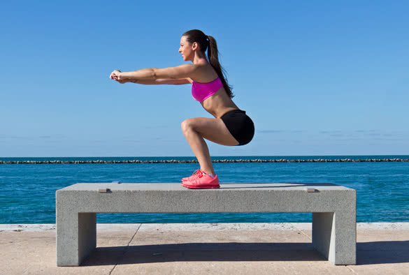 woman-doing-squats-on-a-bench-by-the-ocean