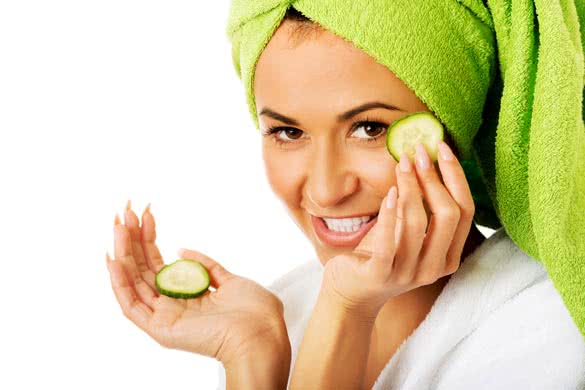 Spa woman in bathrobe applying cucumber on eyes