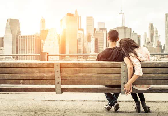 couple relaxing on New york bench in front of the skyline at sunset time