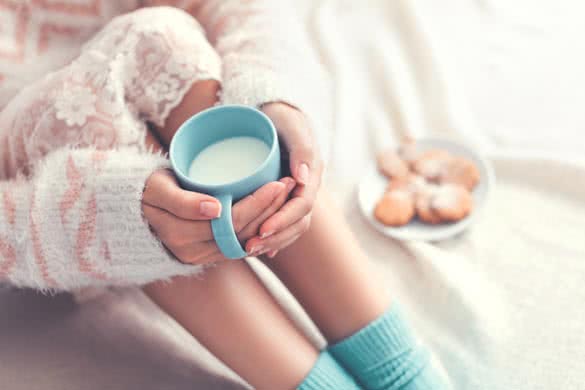 Soft photo of woman on the bed with cup of milk in hands