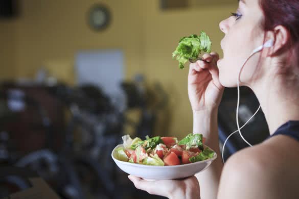 Gorgeous young woman at the gym eating salad