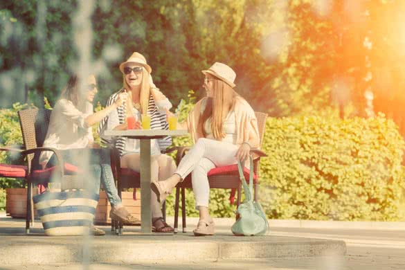 Three attractive girlfriends enjoying cocktails in an outdoor cafe