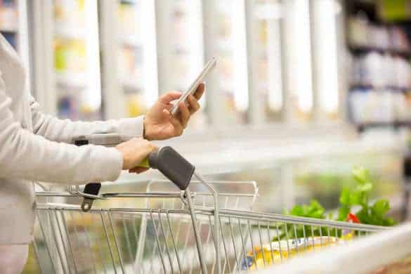 Woman using mobile phone while shopping in supermarket