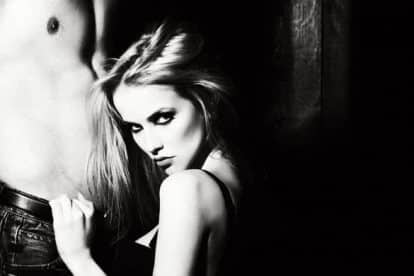 Young sexual couple of attractive blonde woman in bra touching and sitting near handsome man