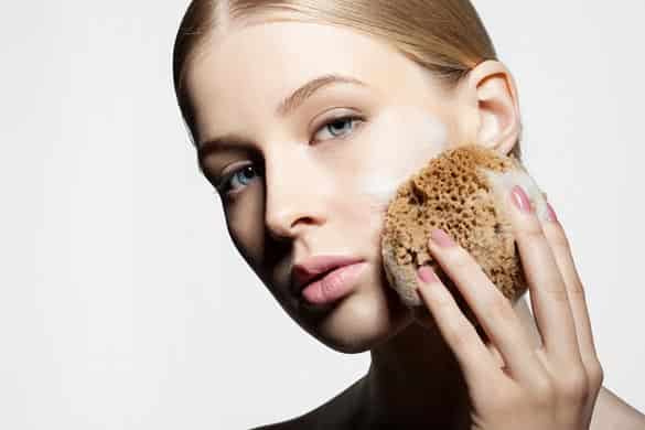 Woman cleans and exfoliates the skin with a natural sponge foam face