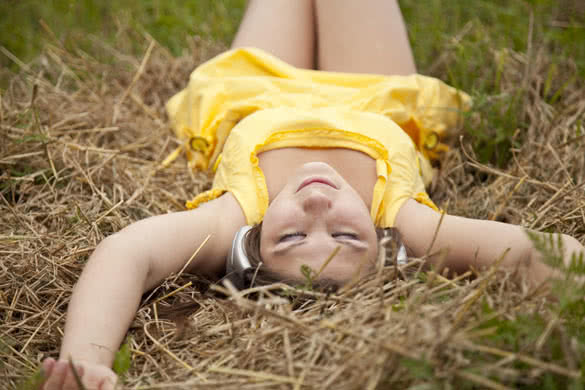 Young beautiful girl in yellow with headphones at field