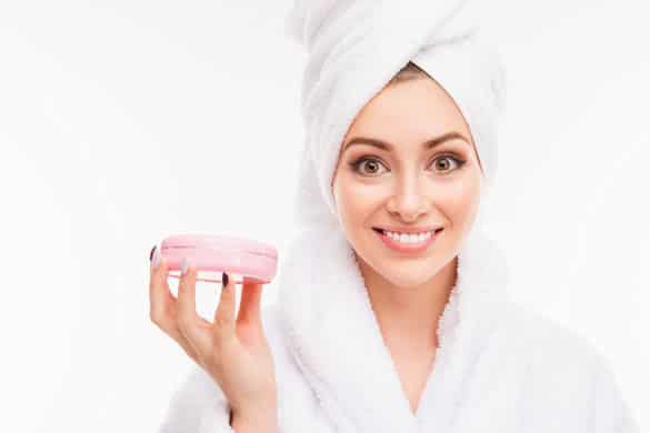 Close up photo of cute girl with towel on her head holding cream