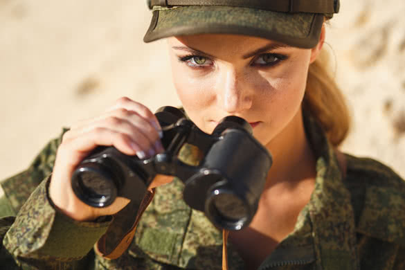 Gorgeous young woman in a Military costume with a binoculars