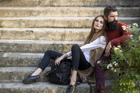 One beautiful stylish couple of young woman and senior man with long black beard sitting embracing close to each other outdoor in autumn street on stairs sunny day