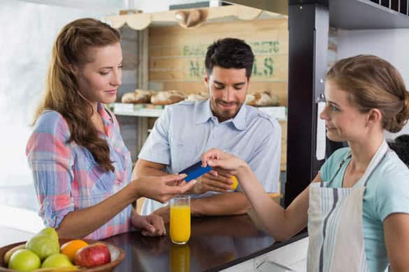 Side view of a couple paying bill at coffee shop using card bill