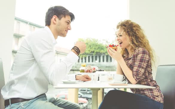 Young happy couple having a coffee break in a pastry shop for some desserts and cappuccino