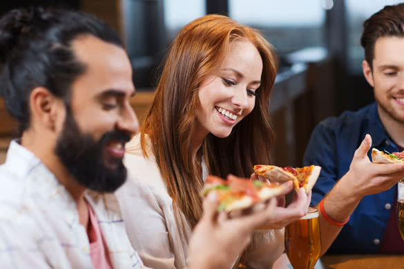 smiling friends eating pizza and drinking beer at restaurant