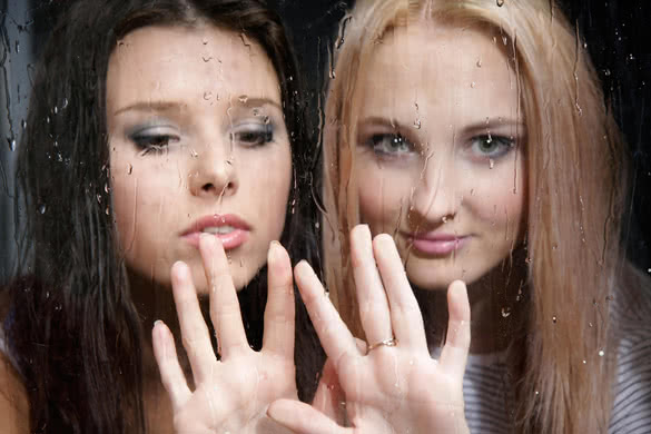 two young girls behind wet window