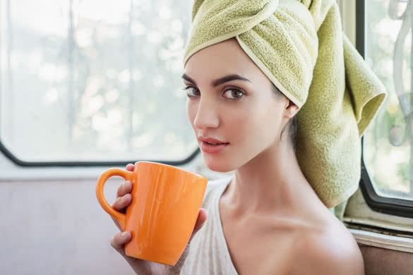 Beautiful young woman with morning cup of hot beverage