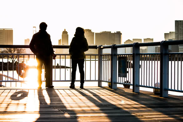 Silhouette of a couple stand on a bridge in the beach at sunset