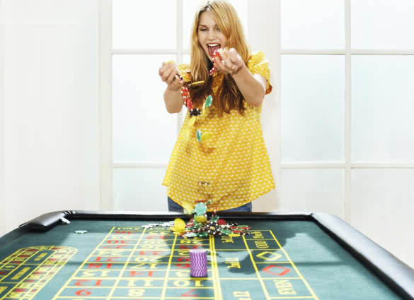 Young woman celebrating with chips on roulette table