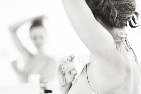 Closeup on woman applying roller deodorant on underarm