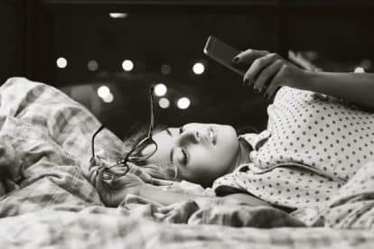 Girl lying in bed and looking at her phone