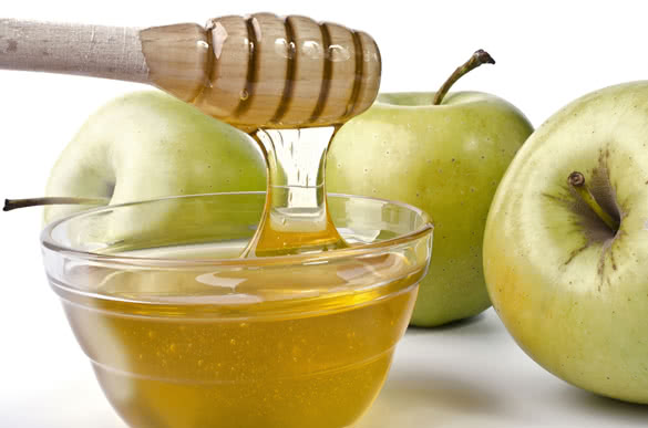 Green apples and a bowl of honey