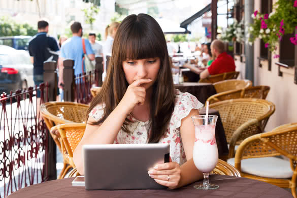 Sad girl in a cafe looking into a tablet