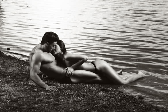 Young sexy couple on beach with sun rising in background