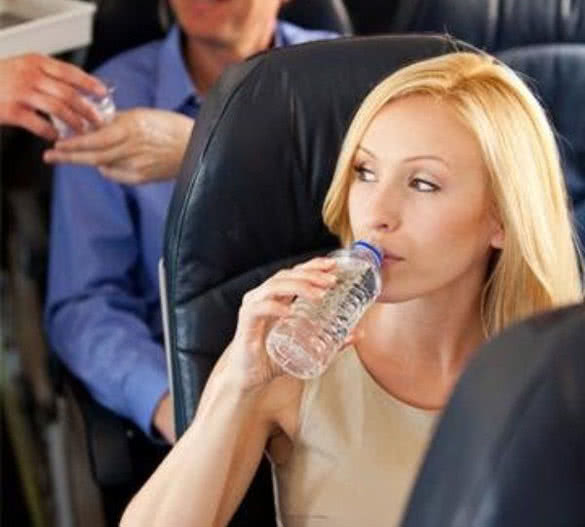blonde woman drinking water on airplane