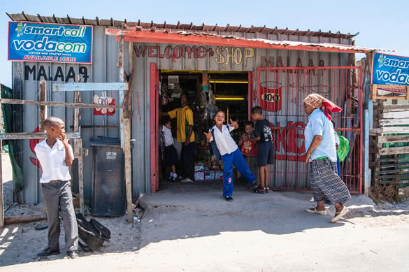 children play and pose for the camera outside a shop in a South African township