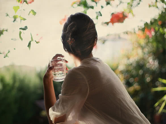 woman looking away and holding a glass of water
