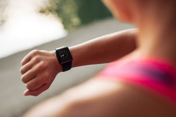 Close up image of young woman checking the time on smartwatch device after jog
