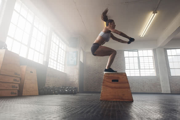 Side view image of fit young woman doing a box jump exercis