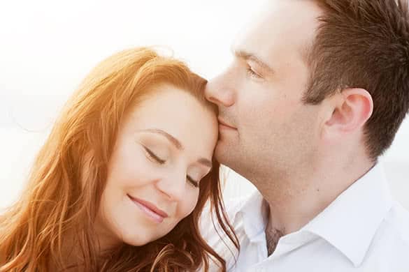 man kissing woman on a forehead