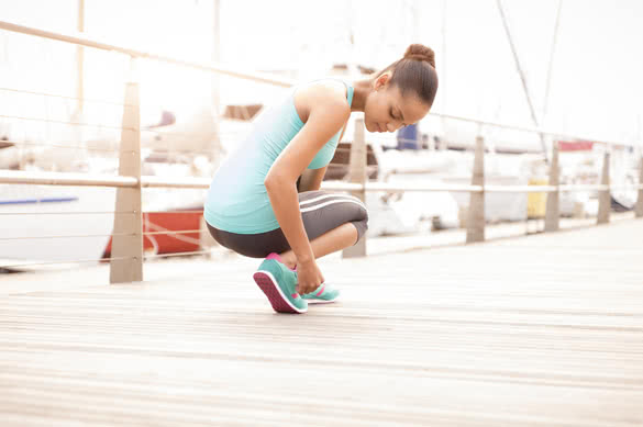 young attractive girl tying her running shoes before a morning exercise