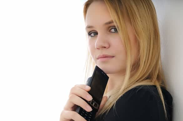 Blond thoughtful young woman holding mobile phone