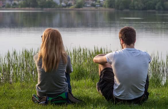 Boy and girl sitting on the bank of the lake