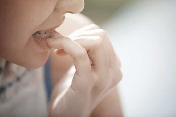 Close-up view on the woman biting nails