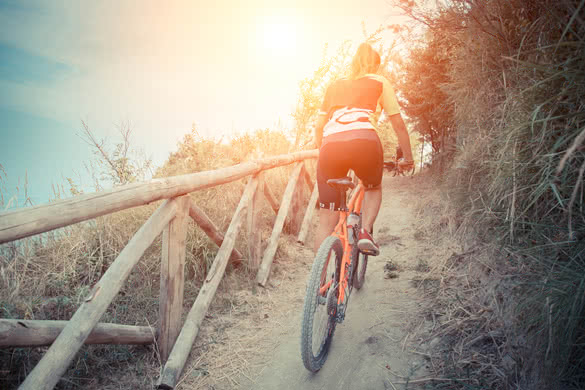 Cyclist pedaling uphill with a backdrop of the sea at sunset