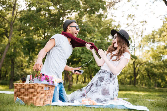 Happy young couple having fun and listening to music from smartphone on picnic