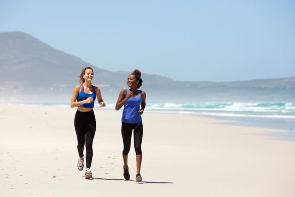Portrait of two happy young women jogging on the beach