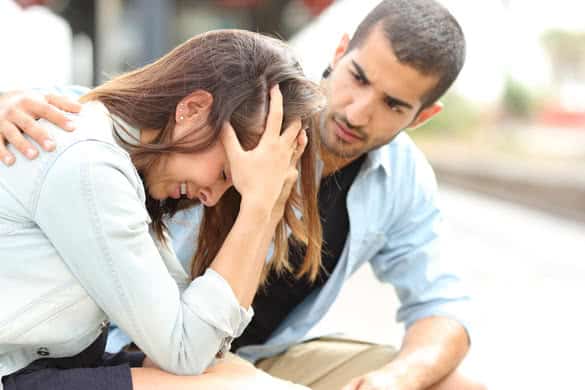 Side view of a muslim man comforting a sad caucasian girl mourning in a train station 2