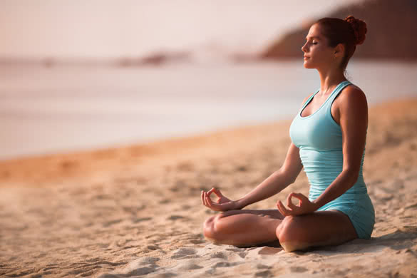 Young beautiful healthy woman making meditation on the beach