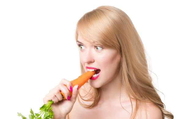 Young happy woman eating carrots