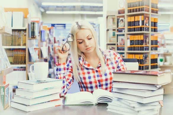 Young pretty woman studying in library