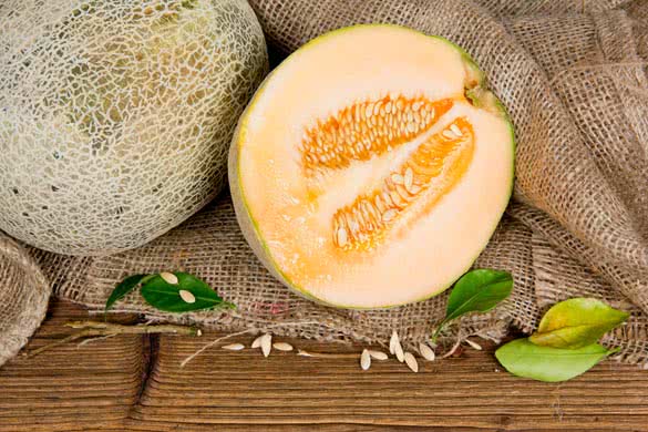 cantaloupe melon with slice and leaves on burlap and wooden board