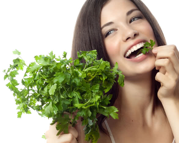portrait of attractive caucasian smiling woman isolated on white studio shot eating salat parsley