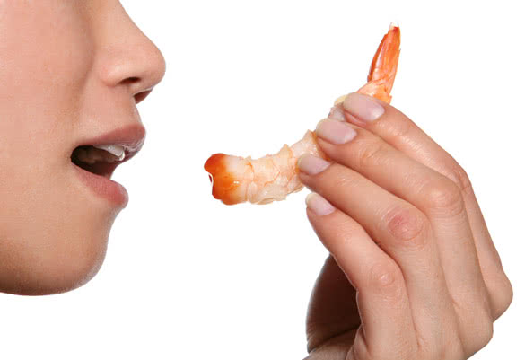 A woman eating a jumbo shrimp