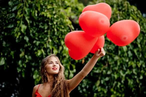 Beautiful woman with bunch of hearts outdoors